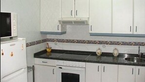 A kitchen with white cabinets, a black countertop, and a microwave. - Loft Amplio con Garaje en Calle Rey Aurelio en Cangas de Onís (Cangas de Onís)