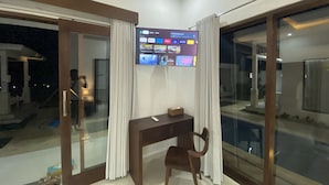 Una habitación moderna con escritorio, silla y un televisor grande que muestra diversos servicios de streaming.