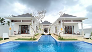 Una casa moderna de dos pisos con una piscina al frente.