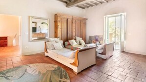 A spacious living room with a wooden ceiling, a large sofa, a wooden cabinet, and a view through a glass door. - Painter's Garden (Toscana)