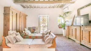 A cozy living room with a sofa, wooden cabinets, and a television. - Painter's Garden (Toscana)
