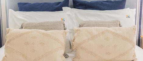 A bed with four pillows, two blue and two beige, and a headboard.