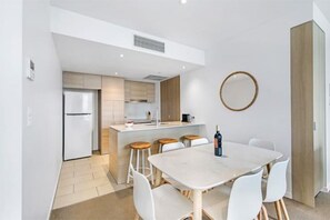 Une cuisine moderne avec un îlot central, des chaises blanches et une table à manger.