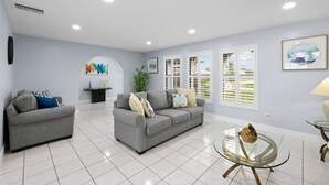 A modern living room with two grey sofas, a glass coffee table, and a white tiled floor. - Villa Carmen (Cape Coral)