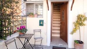 A building entrance with a wooden door, a staircase, a bench, a potted plant, and an air conditioning unit. - Villa Rosa Suite by CorfuEscapes (Corfu)