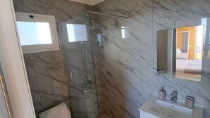 A modern bathroom with a glass-enclosed shower, a toilet, and a vanity with a sink and mirror. - Calheta Countryside - Studio with Balcony (Ilha da Madeira)