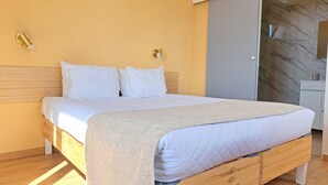 A bedroom with a wooden bed, white bedding, a marble wall, and a sliding door. - Calheta Countryside - Studio with Balcony (Ilha da Madeira)