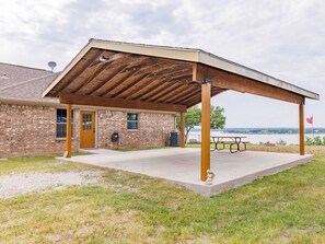 Situated near a serene body of water, this charming building offers a covered patio with a picnic table and a statue.