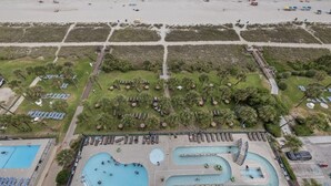 An aerial view of a beach resort with multiple swimming pools, sun loungers, and a beach area with umbrellas and people. - Enjoy the Breathtaking View from Your Private Oceanfront Balcony (Myrtle Beach)