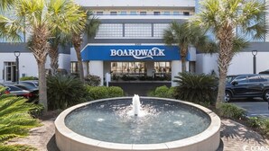 A Boardwalk hotel with a fountain in the center, surrounded by palm trees and a parking lot. - Enjoy the Breathtaking View from Your Private Oceanfront Balcony (Myrtle Beach)