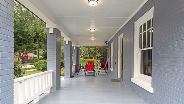 A covered porch with a railing, a table with chairs, and a stop sign in the background. - 3BR Old Mansion in Montrose! Downtown, Medical Center (Houston)