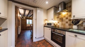 Een keuken met witte kastjes, een magnetron, een oven en een betegelde spatwand.