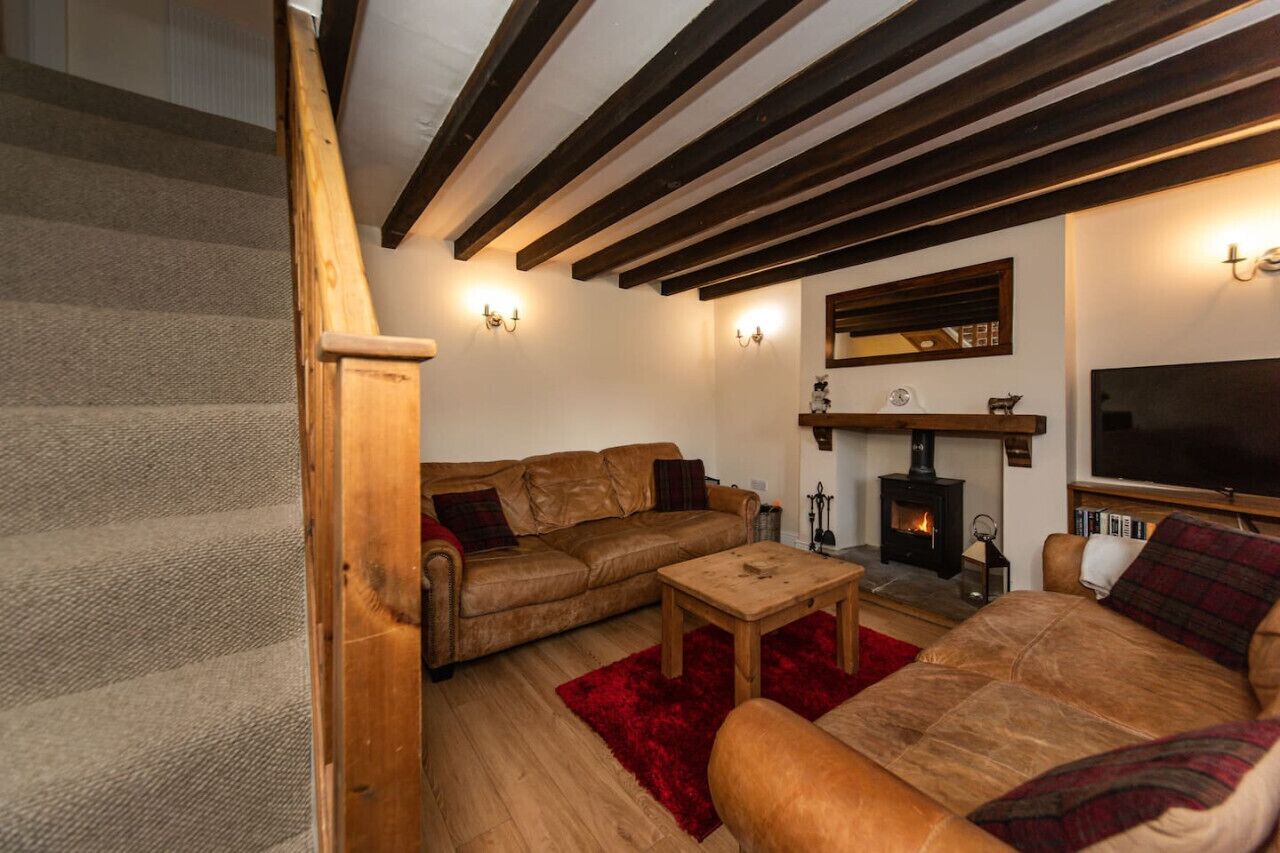 A cozy living room with a fireplace, leather sofas, a wooden coffee table, and a staircase.