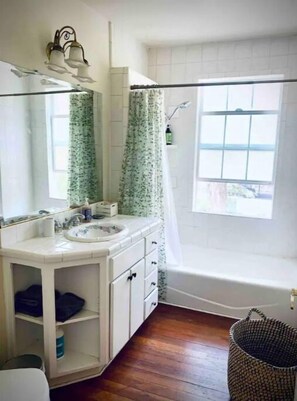 Bathroom features a sink, mirror, and shower curtain with a floral pattern.