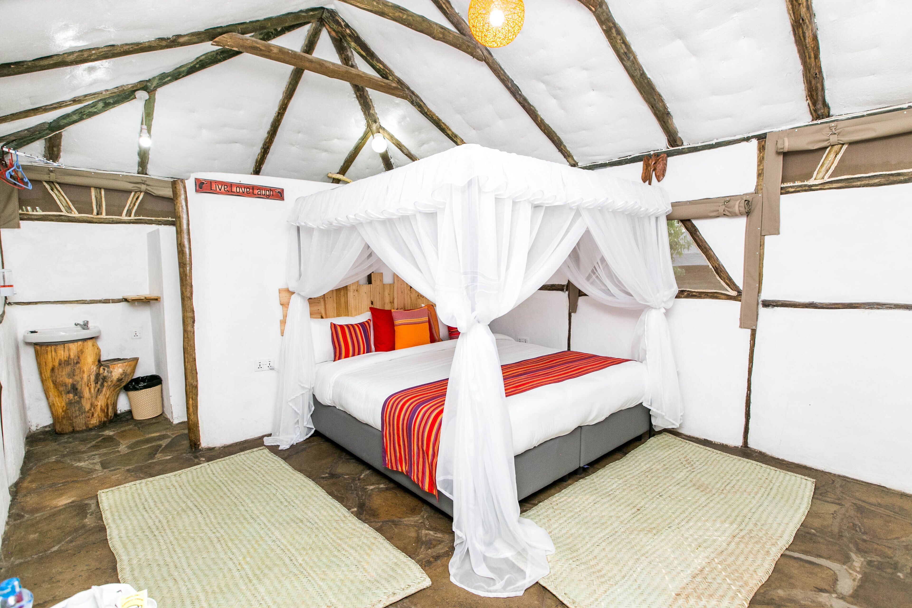 Un dormitorio acogedor con una cama con dosel, suelo de piedra y techo de madera rústica.