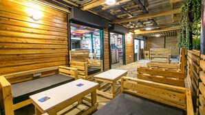 Un'accogliente ambientazione in legno rustico, con panche e tavoli, un ingresso ben visibile e un soffitto con travi a vista.