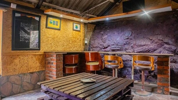 Un intérieur rustique avec une table en bois, des murs en briques et des chaises en métal.