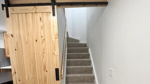 Un escalier dont les marches sont recouvertes de moquette, menant à un palier.