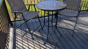 Une terrasse en bois avec une table ronde et deux chaises.