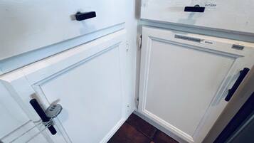 Een keuken met witte kastjes, een besteklade en een rekje voor kruiden.