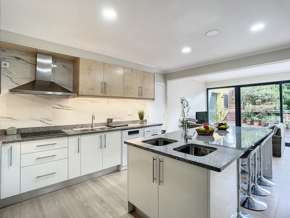 A modern kitchen with white cabinets, granite countertops, and stainless steel appliances. - Solarium Villa by Atlantic Holiday (Machico)