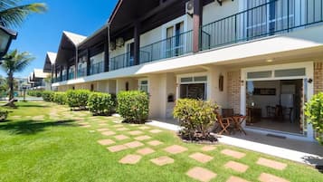 Um hotel com área de estar coberta ao ar livre, um gramado bem cuidado e um céu limpo.