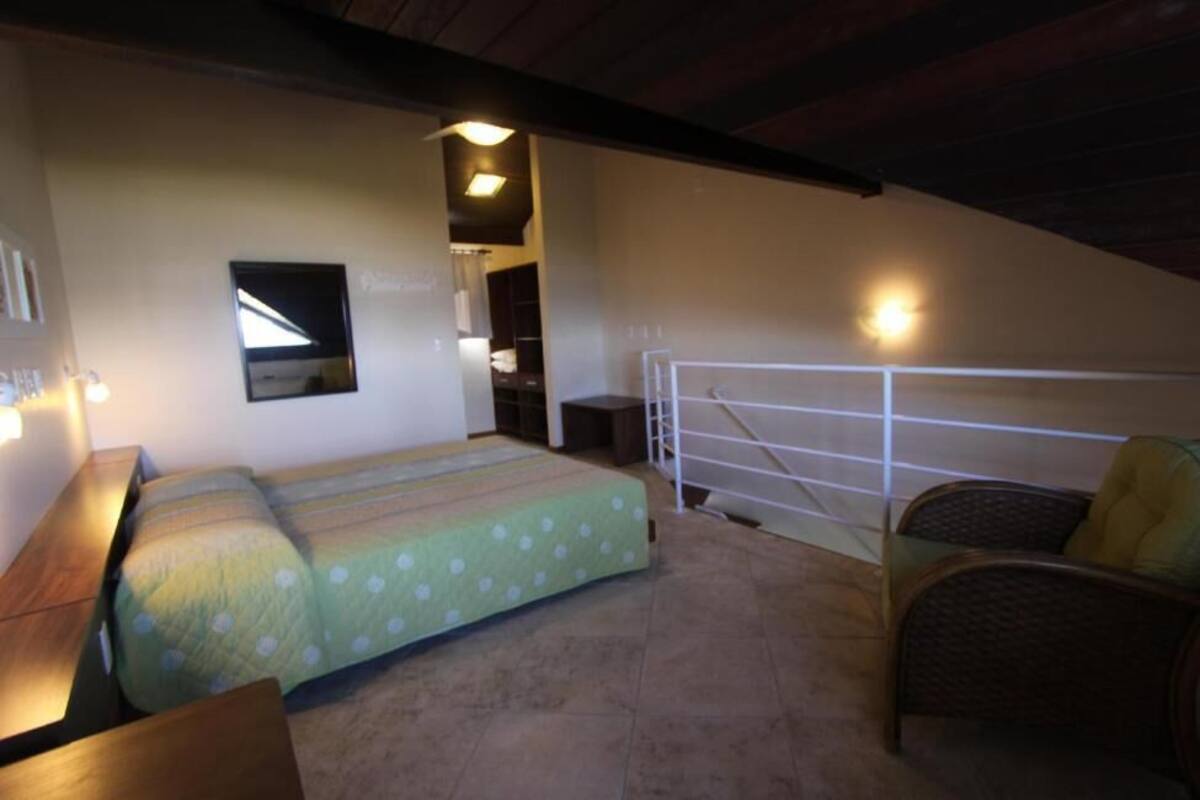 Une chambre avec un lit, une chaise, une barrière blanche et une petite table.