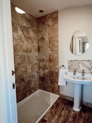 Une salle de bain avec une douche, un lavabo et un miroir.