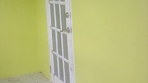 Habitació d'angle amb una porta blanca i una finestra.