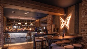 A bar area with wooden furniture, a bar counter, and shelves stocked with bottles. - The Stroud Hotel (Stroud)