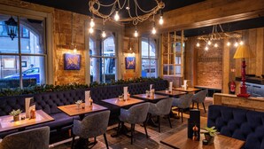 A restaurant with a brick wall, large windows, and a chandelier. Tables and chairs are arranged for dining. - The Stroud Hotel (Stroud)