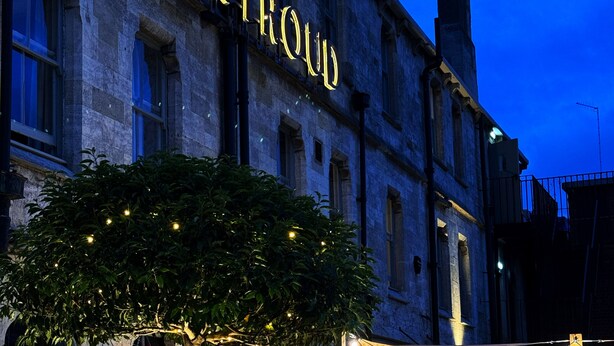 A building with a sign reading "THE STROUD" at night. There is a wooden fence with string lights and outdoor seating. - The Stroud Hotel (Stroud)