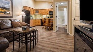 A living room with a brown leather couch, a wooden coffee table, and a painting on the wall. - 1Bed/1Bath - Gorgeous Flagstaff Location with Pools, Golf, and More! (Flagstaff)
