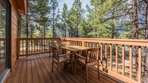 A wooden deck with a table and chairs, surrounded by a railing, overlooking a forest. - 1Bed/1Bath - Gorgeous Flagstaff Location with Pools, Golf, and More! (Flagstaff)