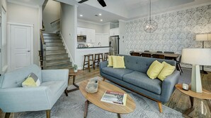 A modern living room with a sofa, coffee table, and a staircase leading to a kitchen.