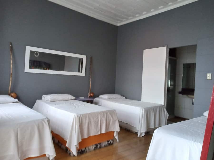 Een hotelkamer met drie eenpersoonsbedden, een grote spiegel en een kledingkast.