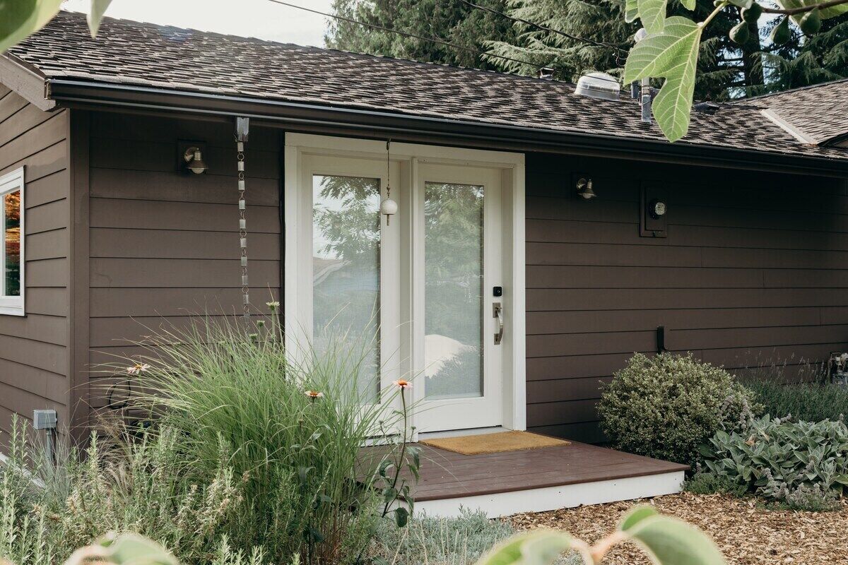 A single-story house with a brown exterior, a white front door, and a small porch.