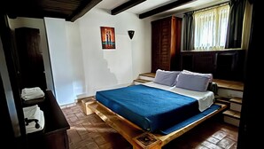 Un dormitorio con una cama de madera, una mesita de noche, un cuadro en la pared y una ventana con cortinas.