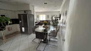 A modern kitchen with a central island, a refrigerator, and a dining area with chairs. - GuestHome 5 minutes from Miami Airport with Heated Pool  (Miami)