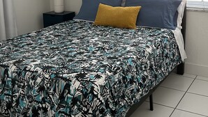 A bedroom with a bed, a ceiling fan, a window with blinds, a nightstand with a lamp, and a wall-mounted abstract painting. - GuestHome 5 minutes from Miami Airport with Heated Pool  (Miami)