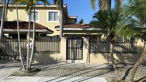 A residential building with a gated entrance, a tiled roof, and palm trees. - GuestHome 5 minutes from Miami Airport with Heated Pool  (Miami)