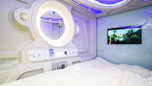 Un dormitorio moderno con una cama grande, televisor integrado y un espejo circular.