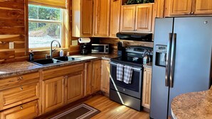 Una cocina con armarios de madera, un refrigerador de acero inoxidable, una estufa y un microondas.