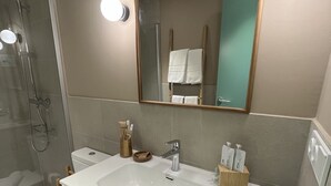 Un baño moderno con lavamanos blanco, un espejo y ducha.