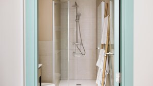 Un baño moderno con ducha envuelta en vidrio, inodoro y barra para toallas.
