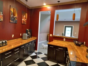 A kitchen with black and white checkered flooring, wooden countertops, and dark cabinets.