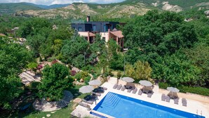 A modern house with a swimming pool, surrounded by lush greenery and hills. - Giuaani Winery (Sagarejo)