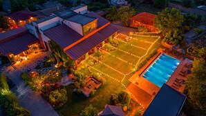 An aerial view of a residential property with a swimming pool, a well-lit garden, and multiple houses. - Giuaani Winery (Sagarejo)