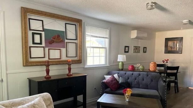 A living room with a sofa, a coffee table, a dark wooden cabinet, and a wall with framed pictures. - Ell's Room (Harkers Island)