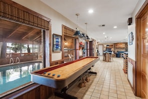A pool table in a room with a view of an outdoor pool, wooden walls, and a kitchen area. - Windy Point Estate - On Lake Istokpoga-5bdr. 5 1/2bath 7 beds. Amazing grounds (Lake Placid)